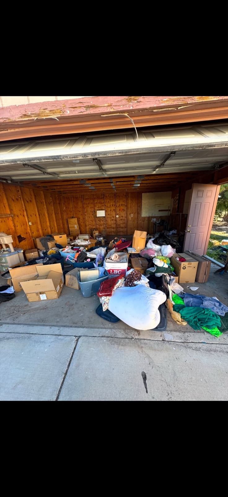 Wood-paneled garage packed with boxes, bags, and household items before JunkMD LV cleanout